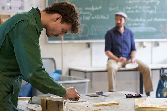 Student an der Akademie für Handwerksdesign Gut Rosenberg erstellt erste Entwurfe während der Dozent weitere Themen erklärt.