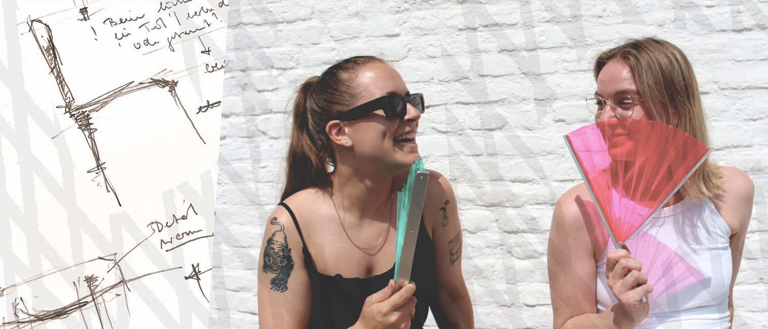 Zwei junge fröhliche Frauen sitzen in der Sonne mit einem Wind-Fächer in der Hand