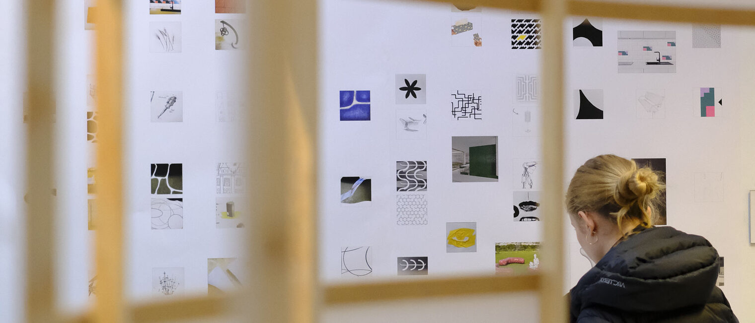 Junge Frau sitzt und arbeitet konzentriert an einem gestalterischem Konzept